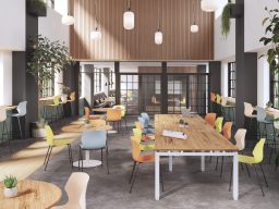 Espace de travail moderne avec tables en bois et chaises colorées, éclairage naturel.