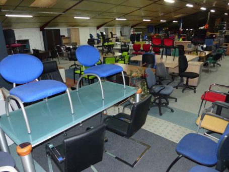 Détail d'un espace rempli de chaises et de tables, certaines empilées.