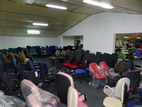 Salle remplie de chaises de bureau de différentes couleurs et styles.