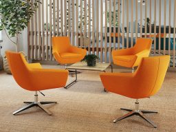 Quatre fauteuils orange autour d'une table basse dans un espace d'accueil.