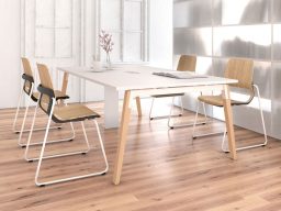 Table blanche moderne avec quatre chaises en bois dans un intérieur lumineux.
