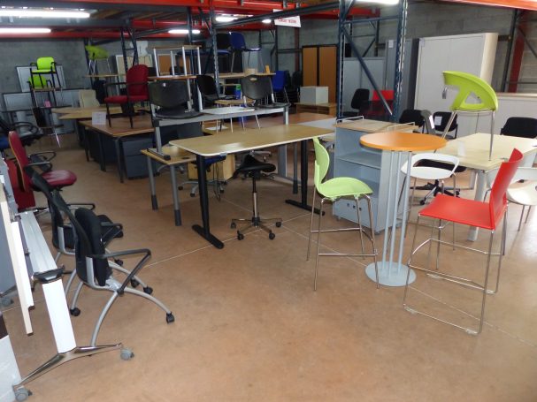 Salle avec plusieurs bureaux et chaises colorées, ambiance de travail moderne.
