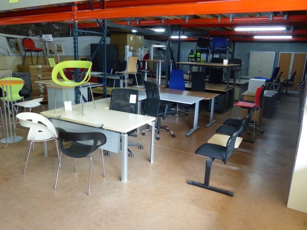 Salle d'exposition de mobilier de bureau avec diverses tables et chaises colorées.