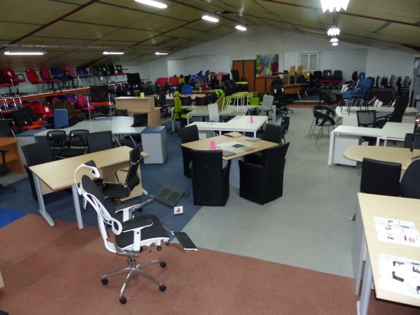Salle d'exposition de meubles de bureau avec des chaises et bureaux disposés.