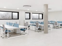 Bureau moderne avec plusieurs stations de travail et chaises blanches et bleues.