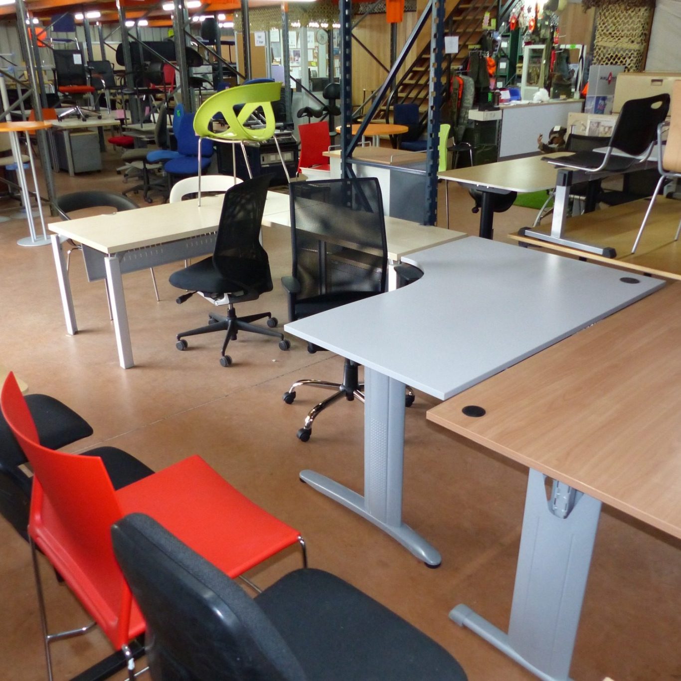 Salle d'exposition avec divers bureaux et chaises modernes, disposés pour l'affichage.
